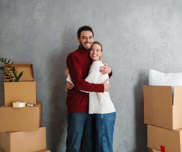 Portrait of a smiling couple moving together in a new house surrounded with boxes, hugging